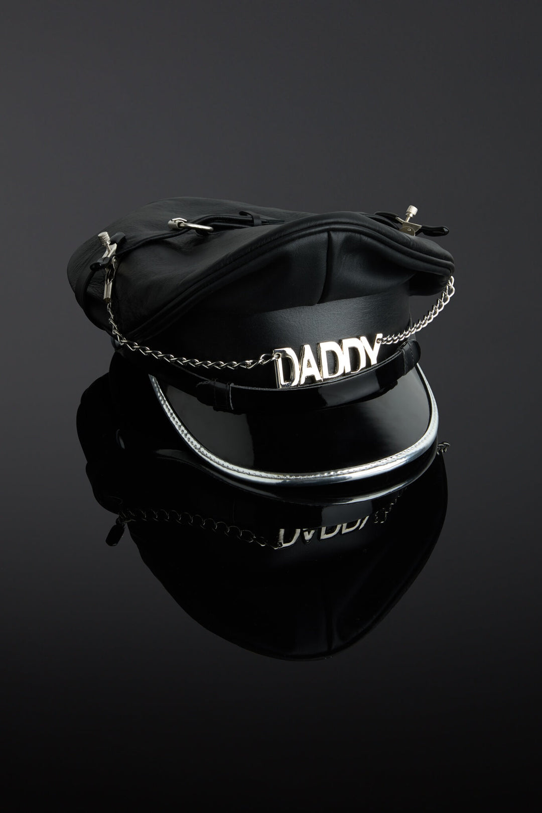 Black leather helmet with 'DADDY' chain on a reflective black surface