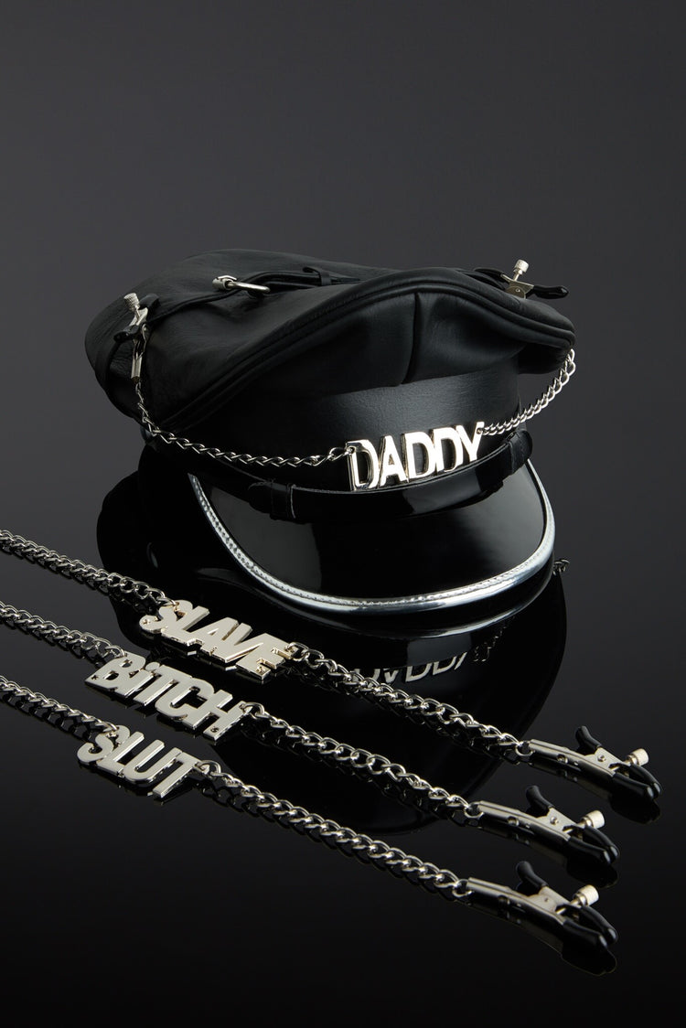Black leather hat with 'DADDY' and chains on a reflective black surface