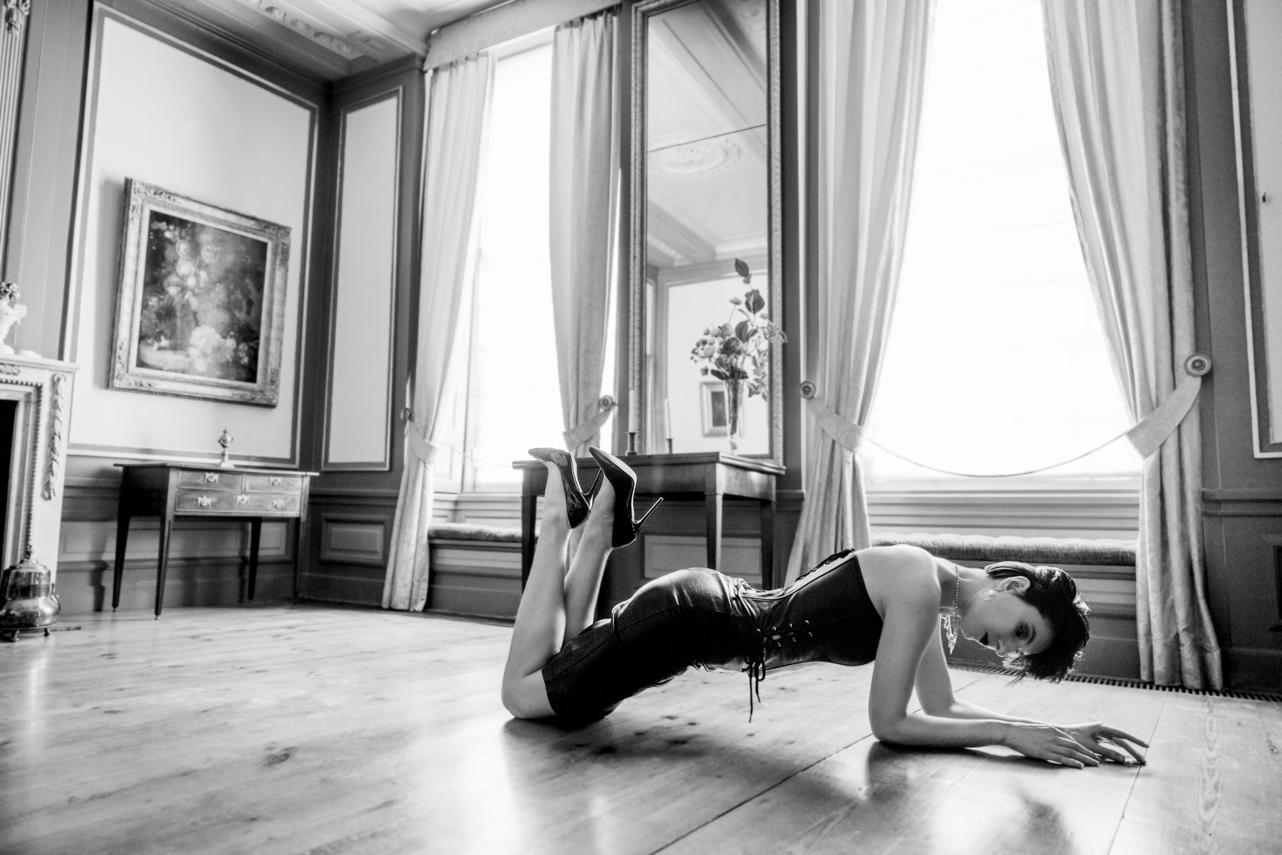 Slideshow picture showing Sara Scarlett Wearing House of SXN black leather dress. She is lying prone on floor. Picture is black and white.