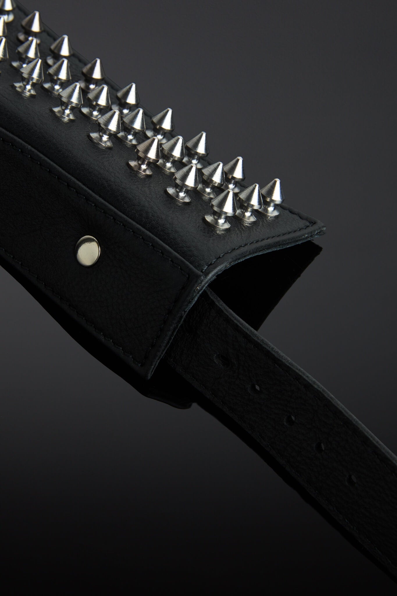 Black leather collar with silver spike details on a dark background