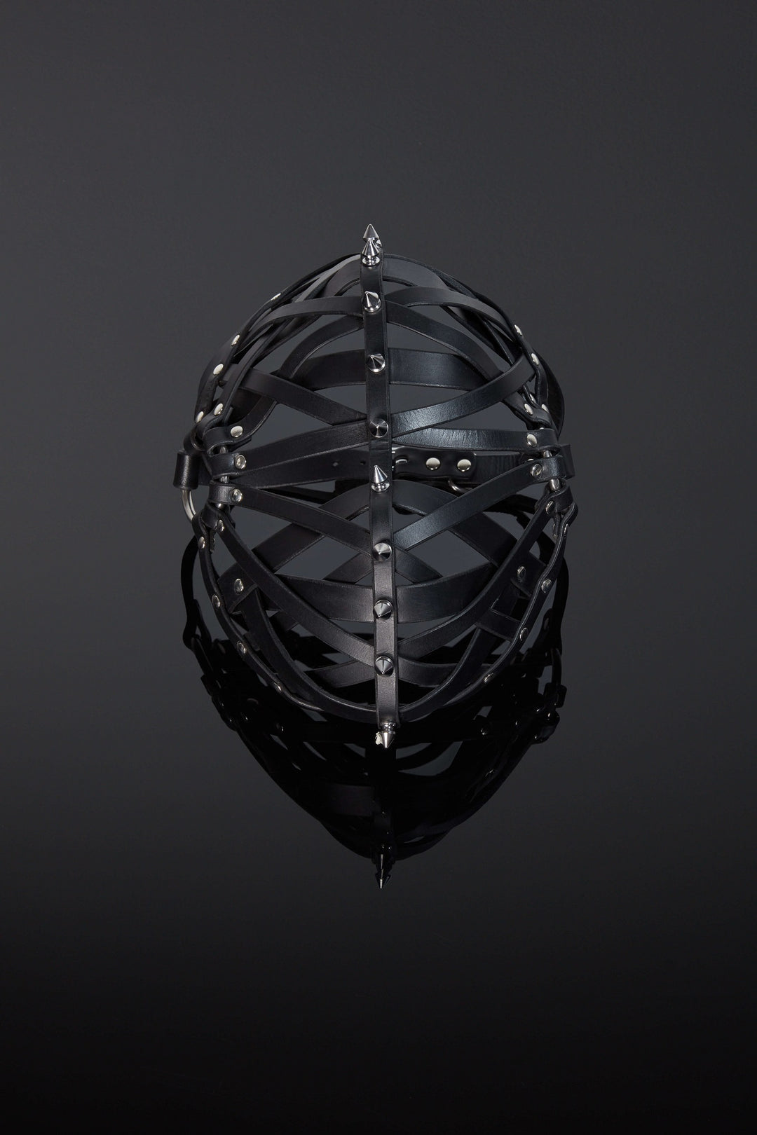 A black leather mask with metal spikes, featuring full grain leather straps woven in a symmetrical design.