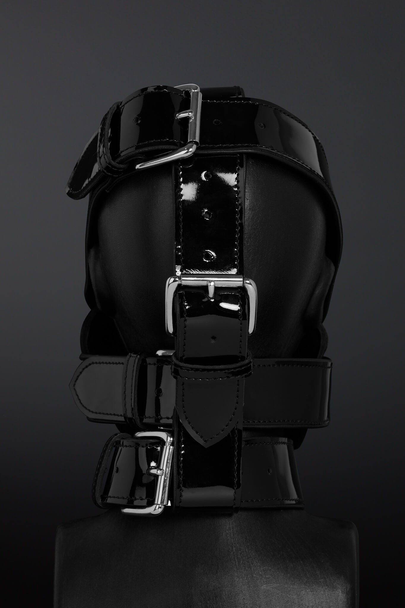 Black leather straps with silver buckles on a dark background