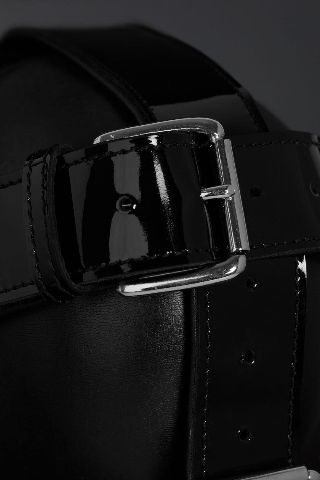 Close-up of a black leather straps with a silver buckle on a dark background