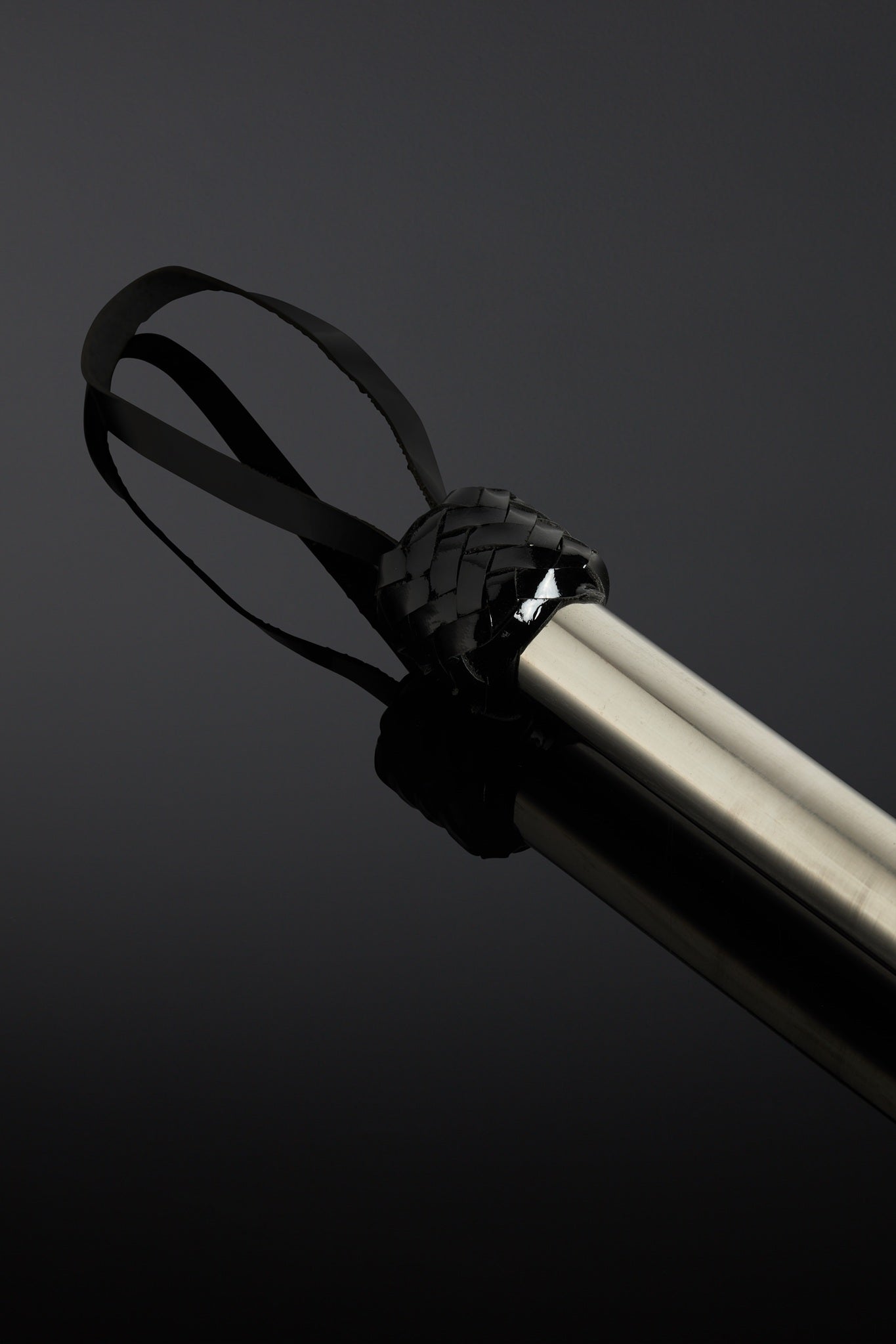 Close-up of a black wrist strap with a metal handle on a dark background