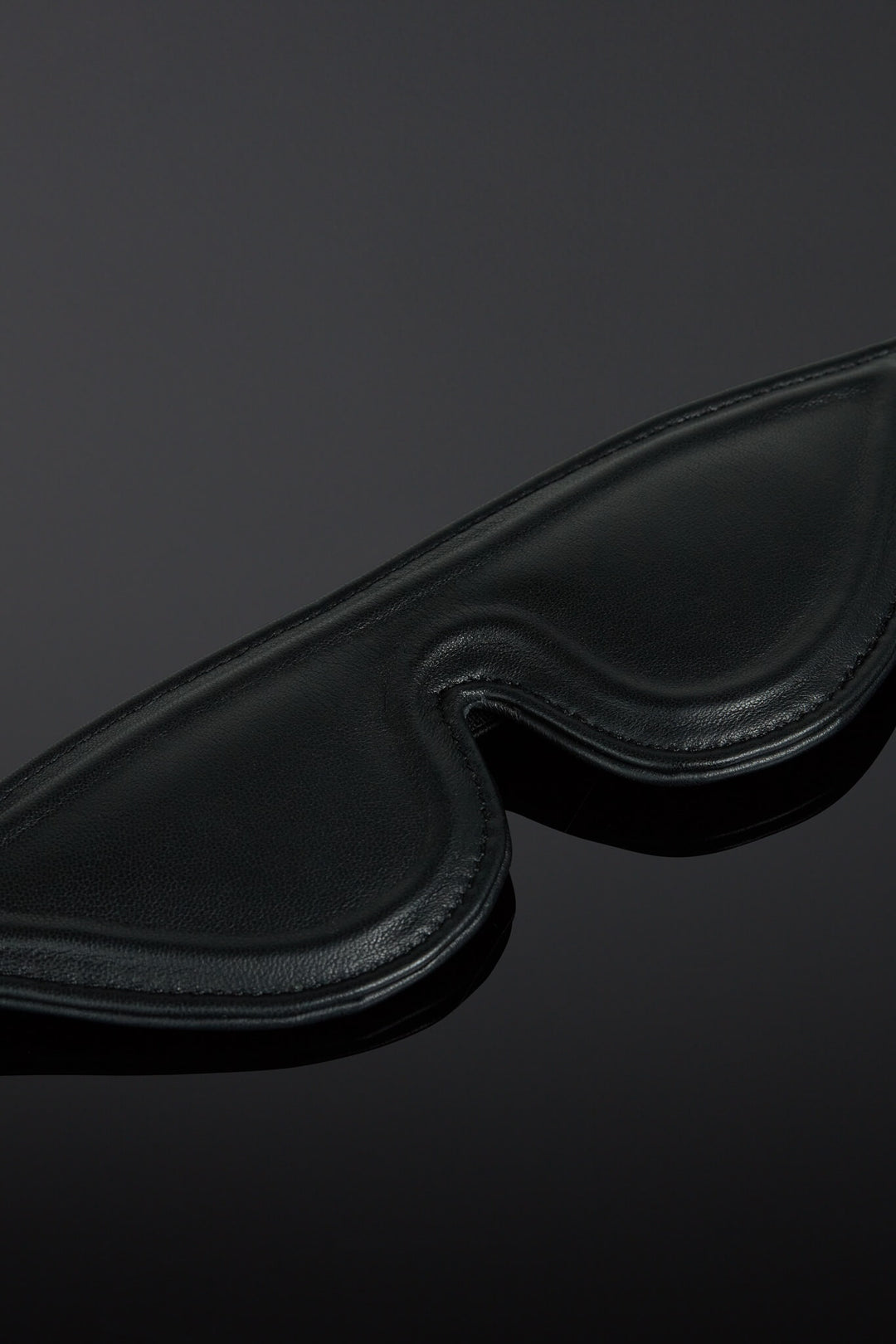 Black leather eye mask on a dark background