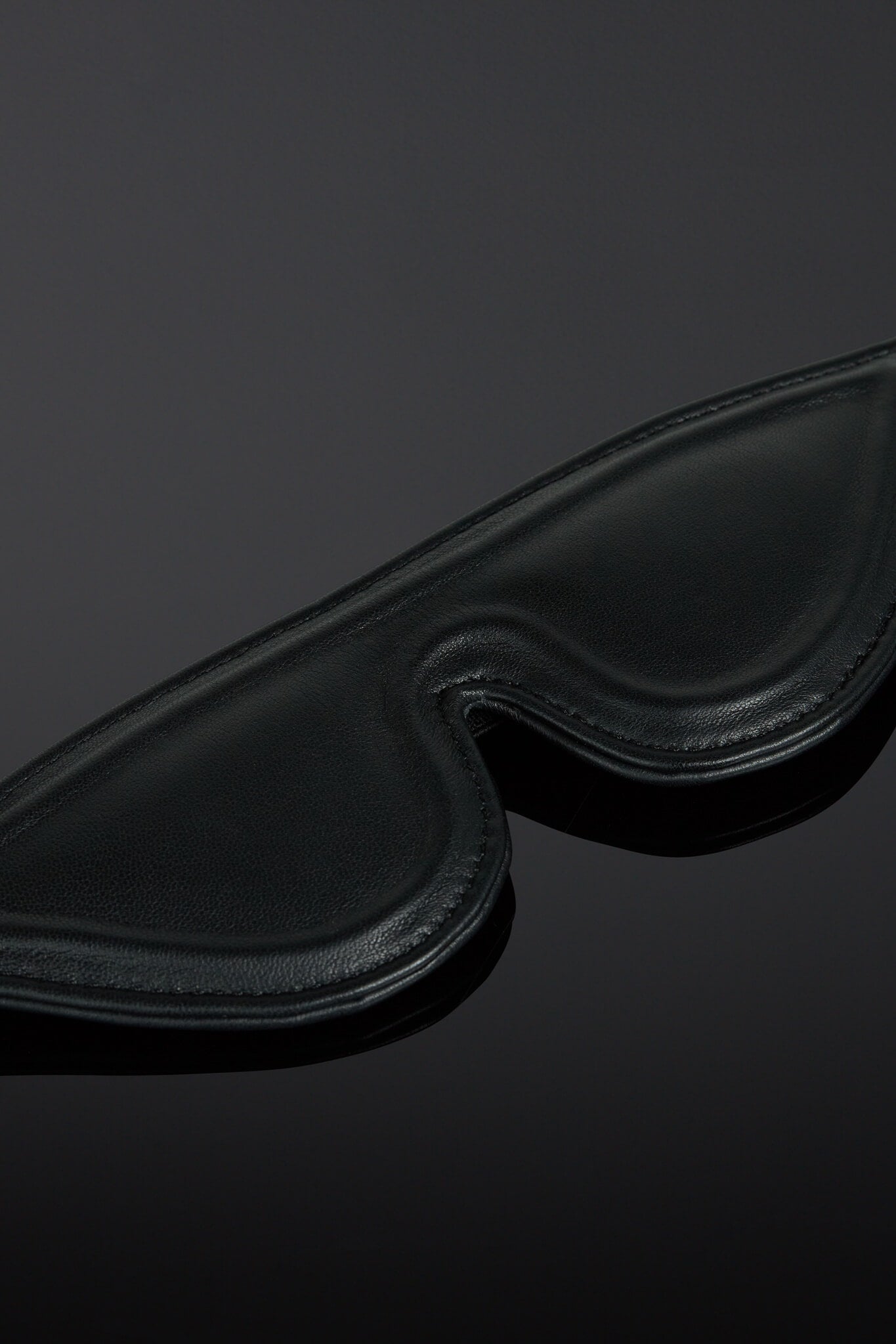 Black leather eye mask on a dark background
