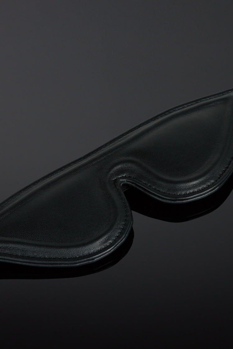 Black leather eye mask on a dark background