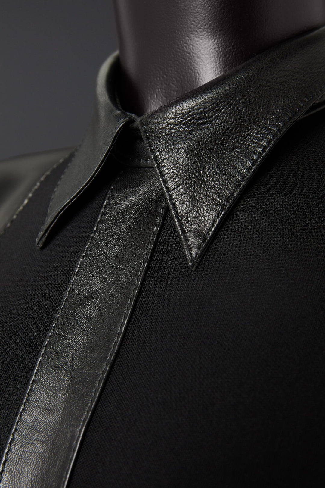 Close-up of a black leather garment with a collar on a dark background