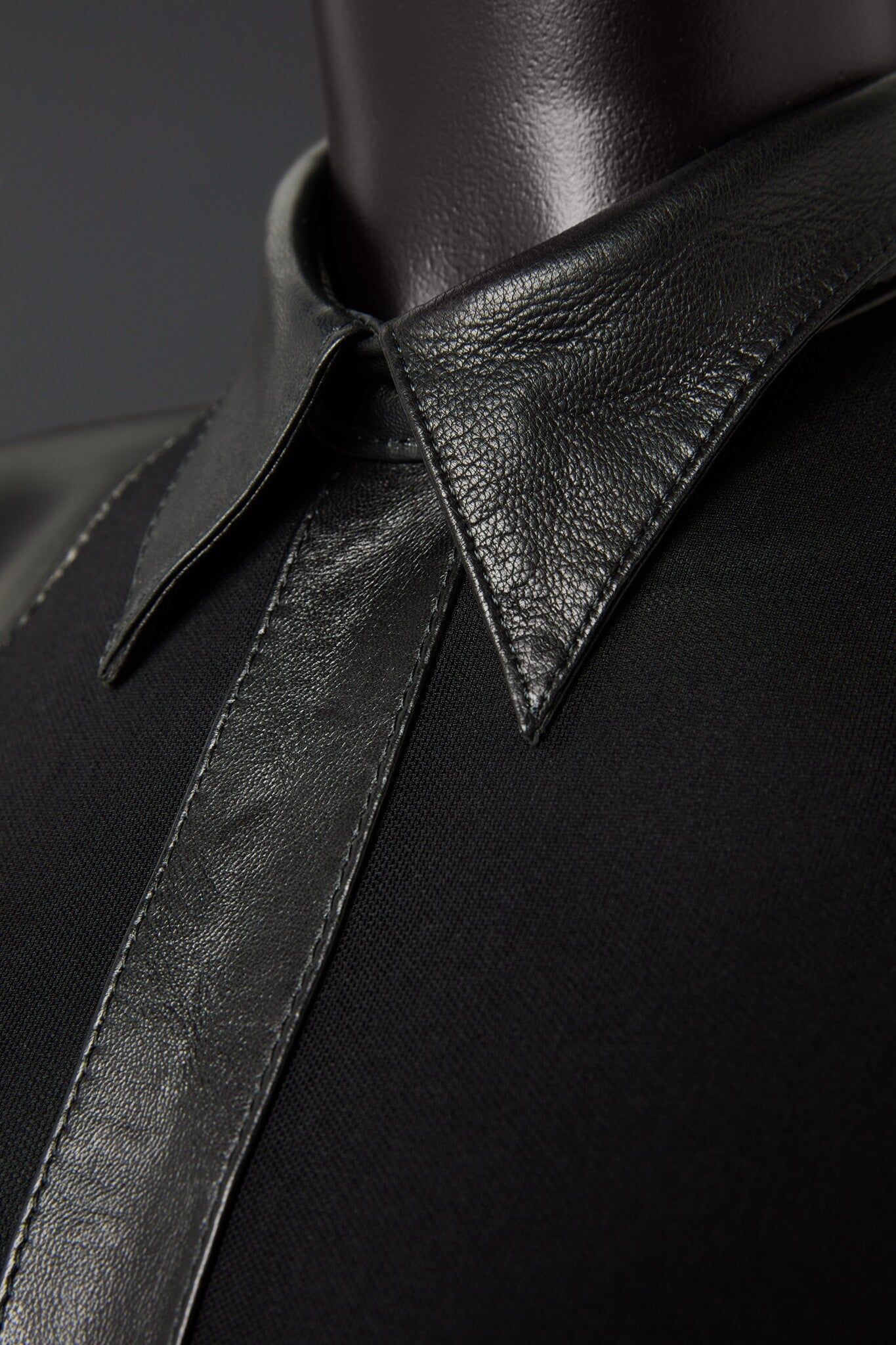 Close-up of a black leather garment with a collar on a dark background