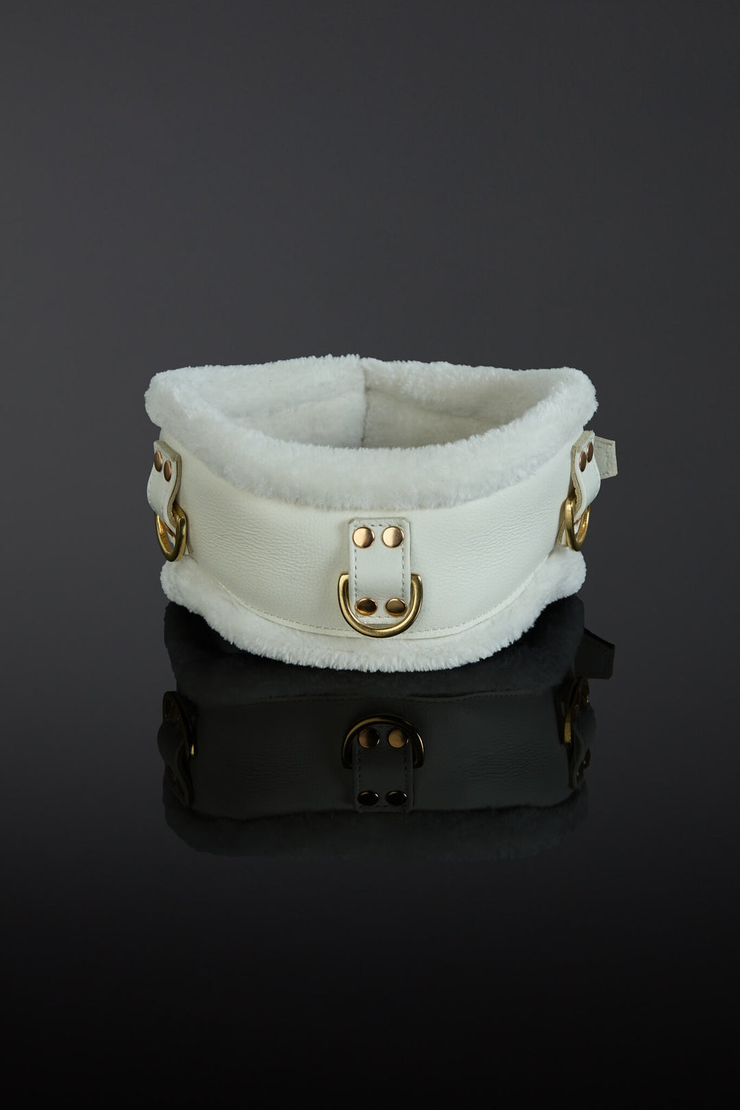 White fur collar with gold hardware on a reflective black surface