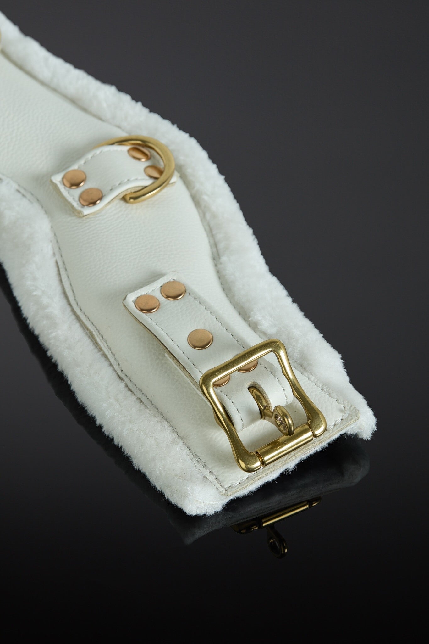 White leather strap with gold buckle on a dark background