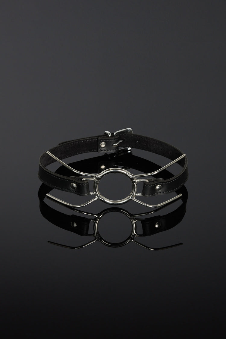 Black leather choker with metal clasp on a reflective black surface