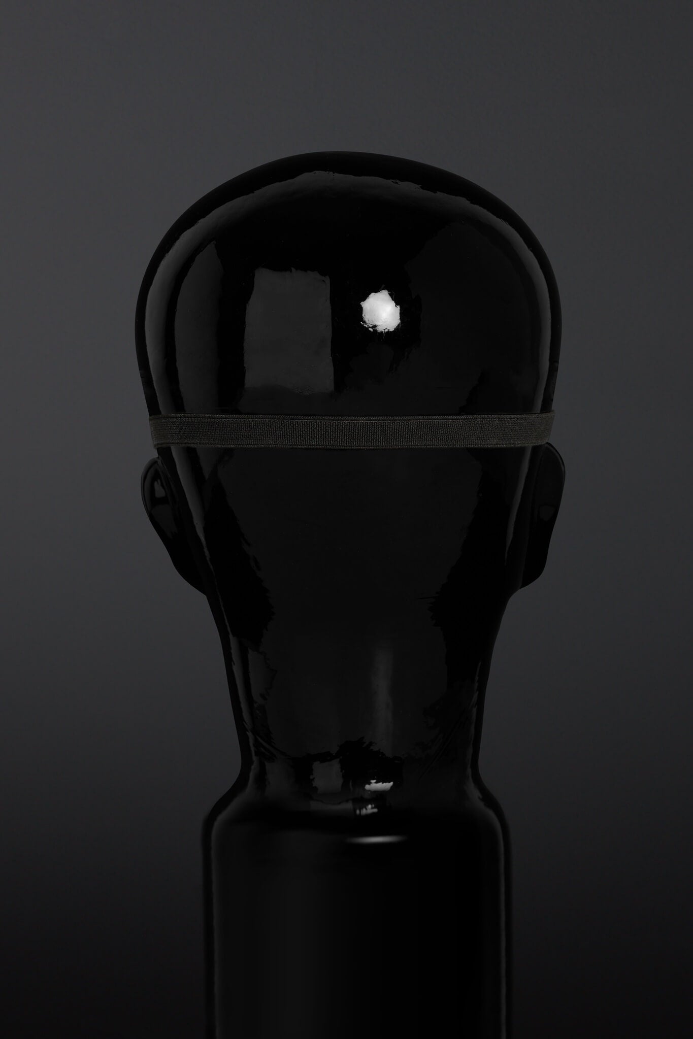 Black blindfold on a dark background - rear of head view