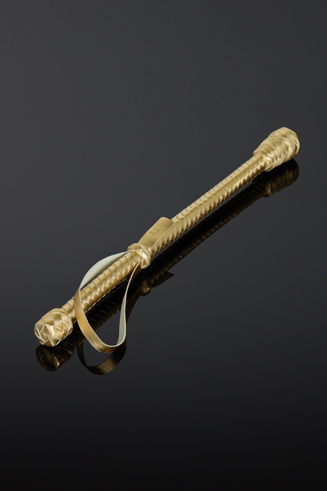 Gold-colored baton with a reflective surface on a black background