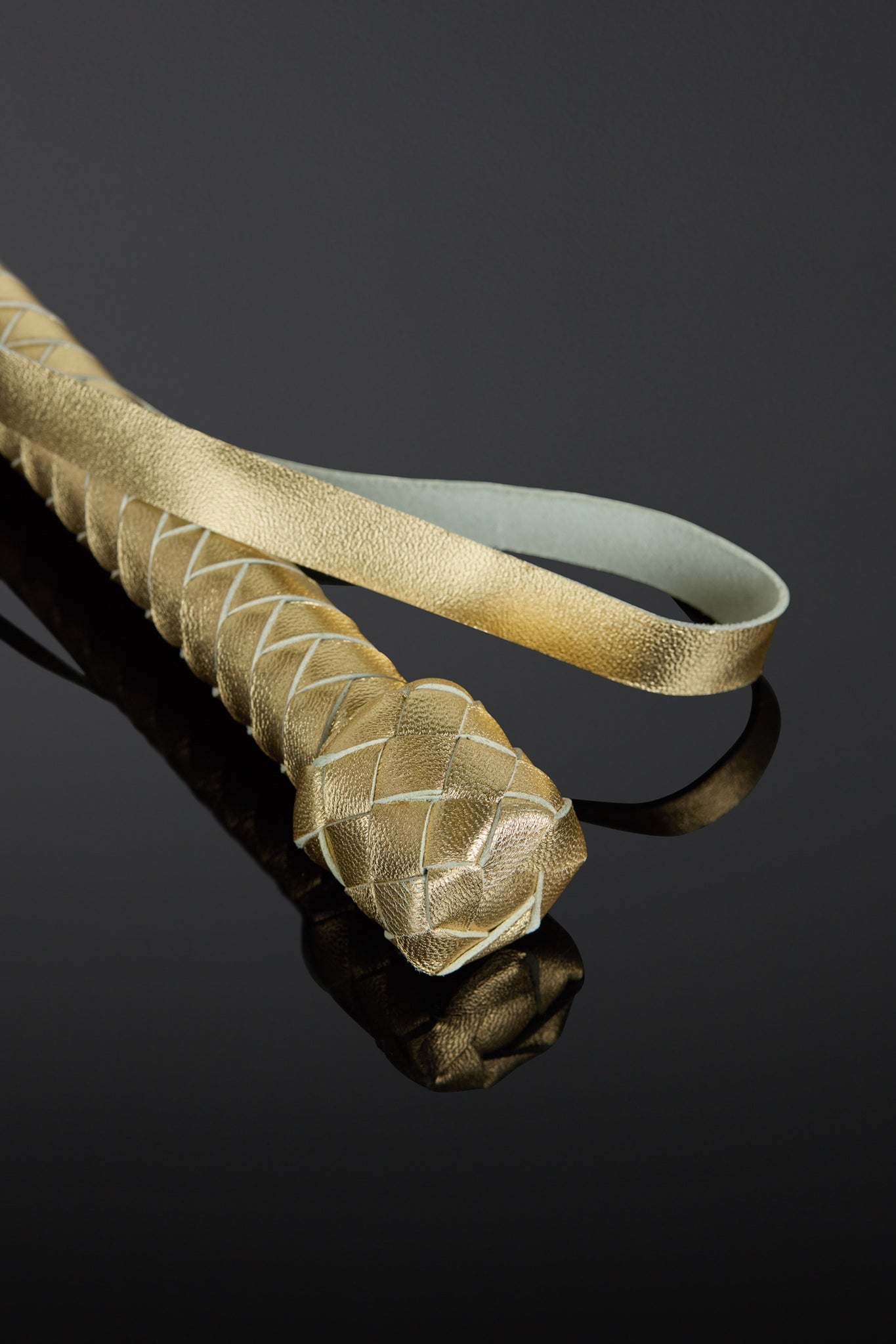 Gold-colored leather wrist strap with a textured pattern on a black background