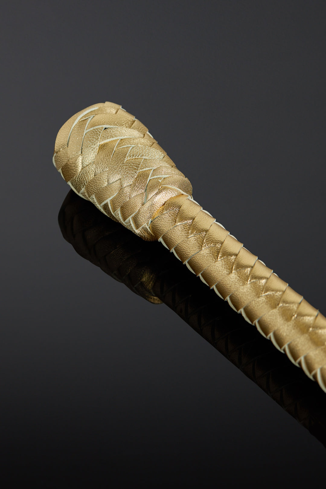Close-up of a braided gold baton on a black background