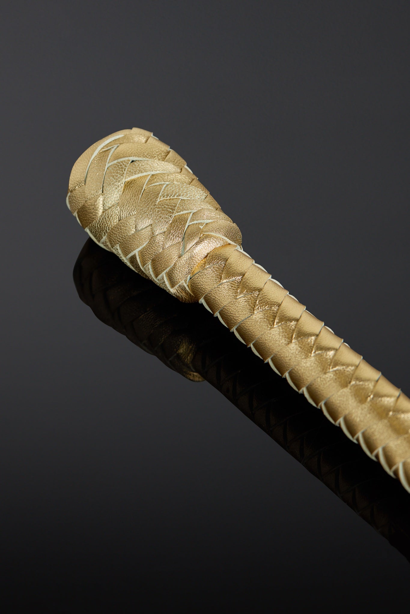 Close-up of a braided gold baton on a black background