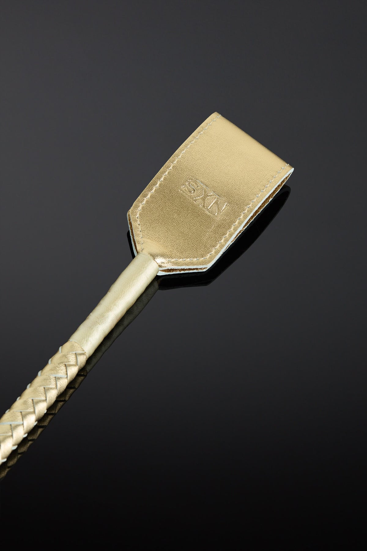 A gold leather crop with metal gold color handle on a black background.  Closeup shot of the head