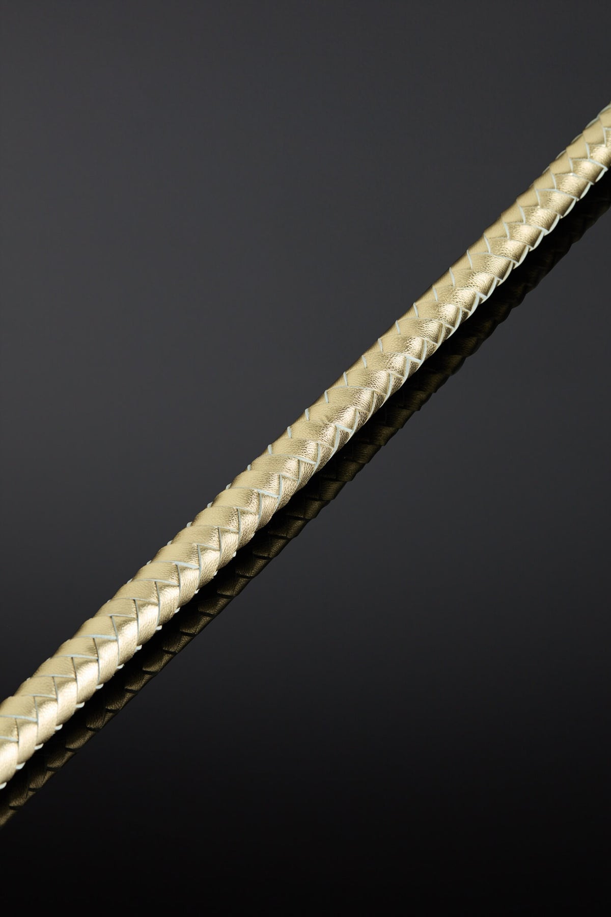A close-up of a gold braided handle running diagonally across a reflective black surface.