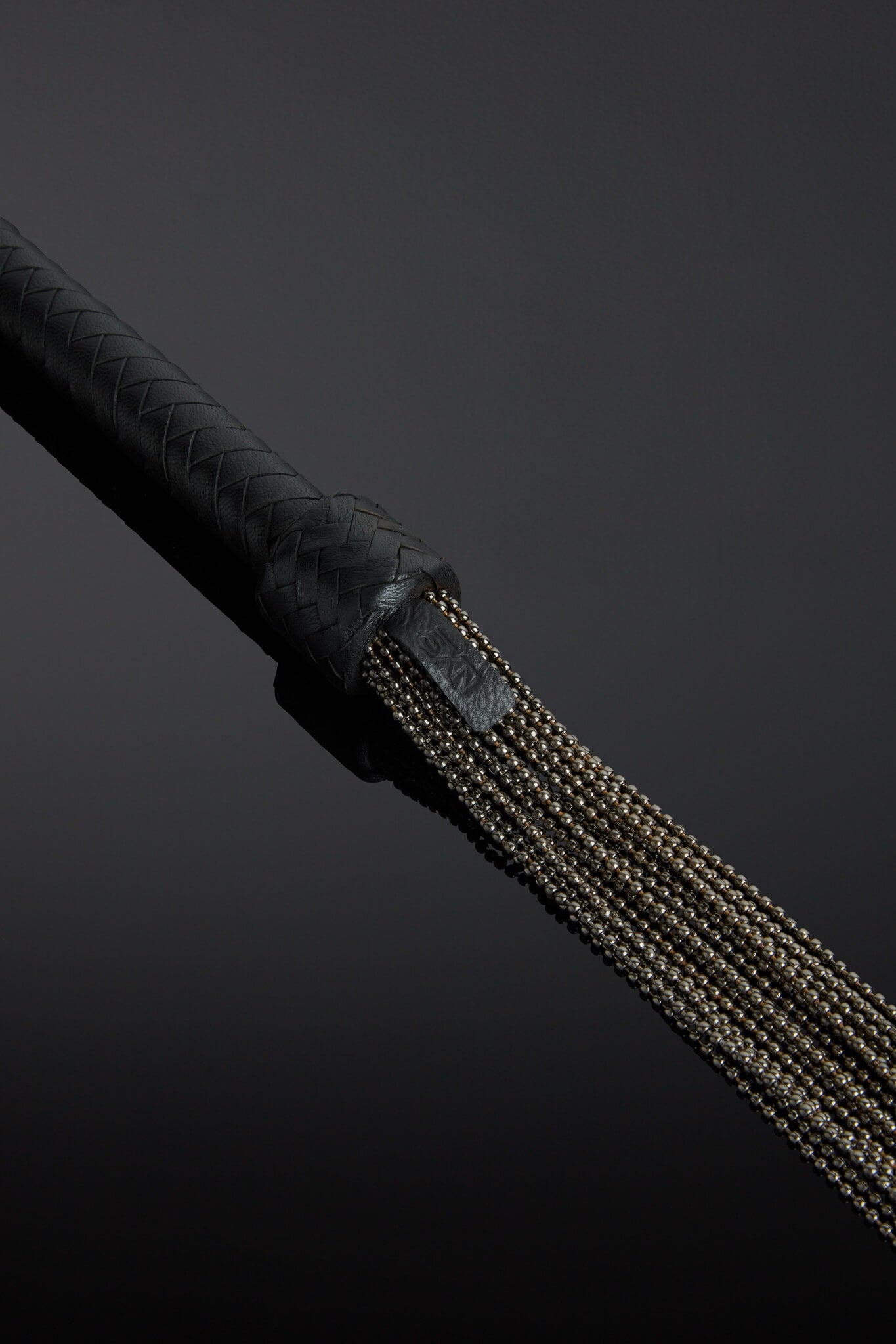 Close-up of a black leather handle with metal chain on a dark background