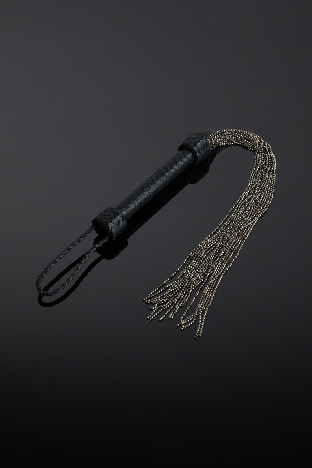 Dark black leather ball chain flogger on black background