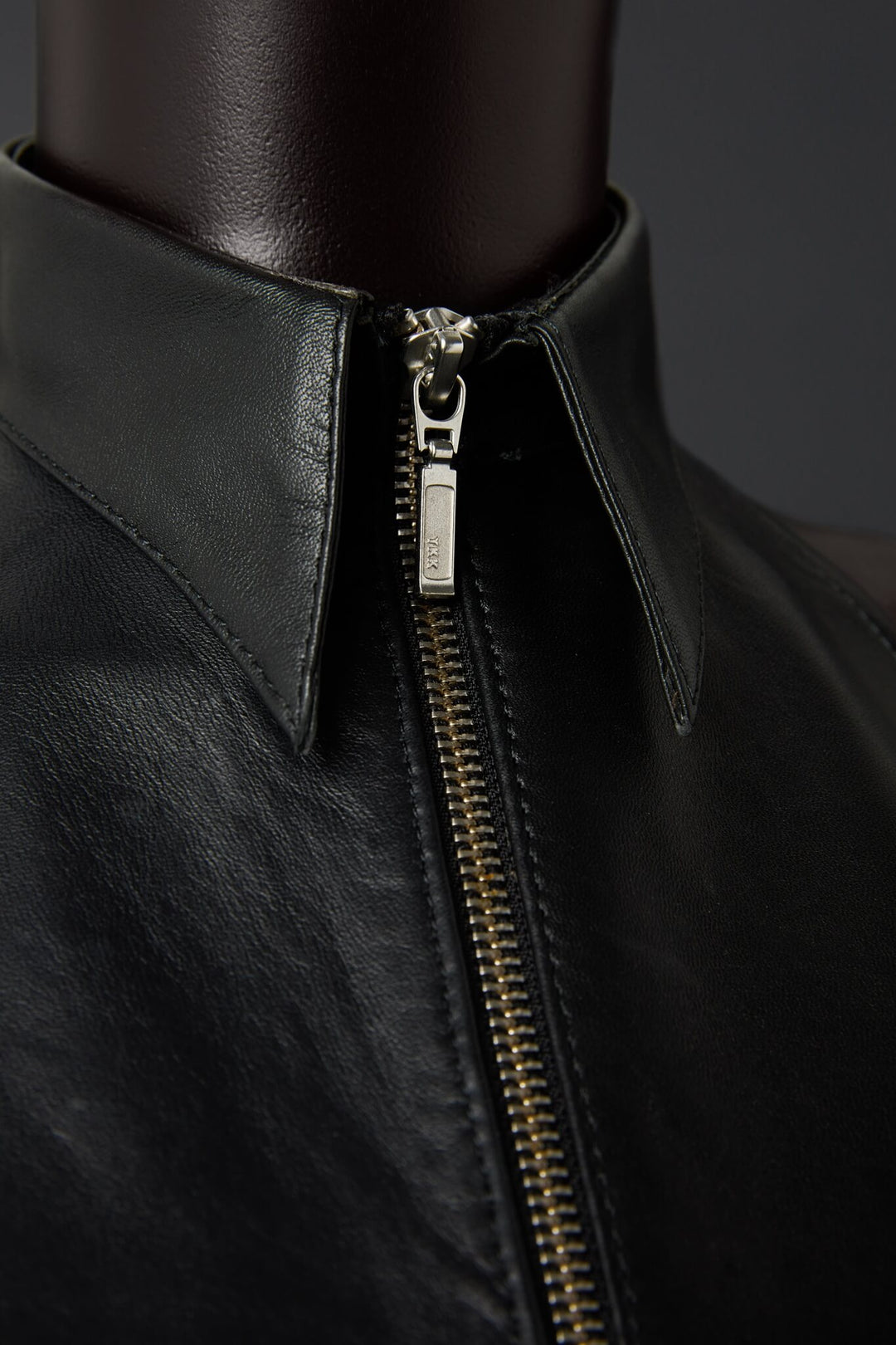 Close-up of a black leather top with a zipper on a dark background