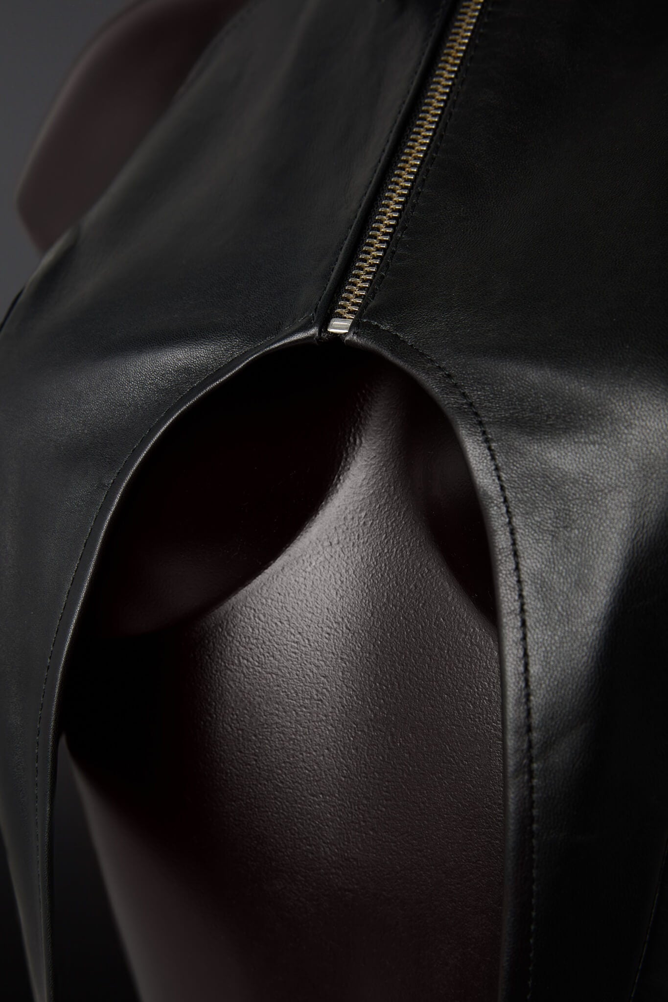Close-up of a black leather top with a zipper detail.