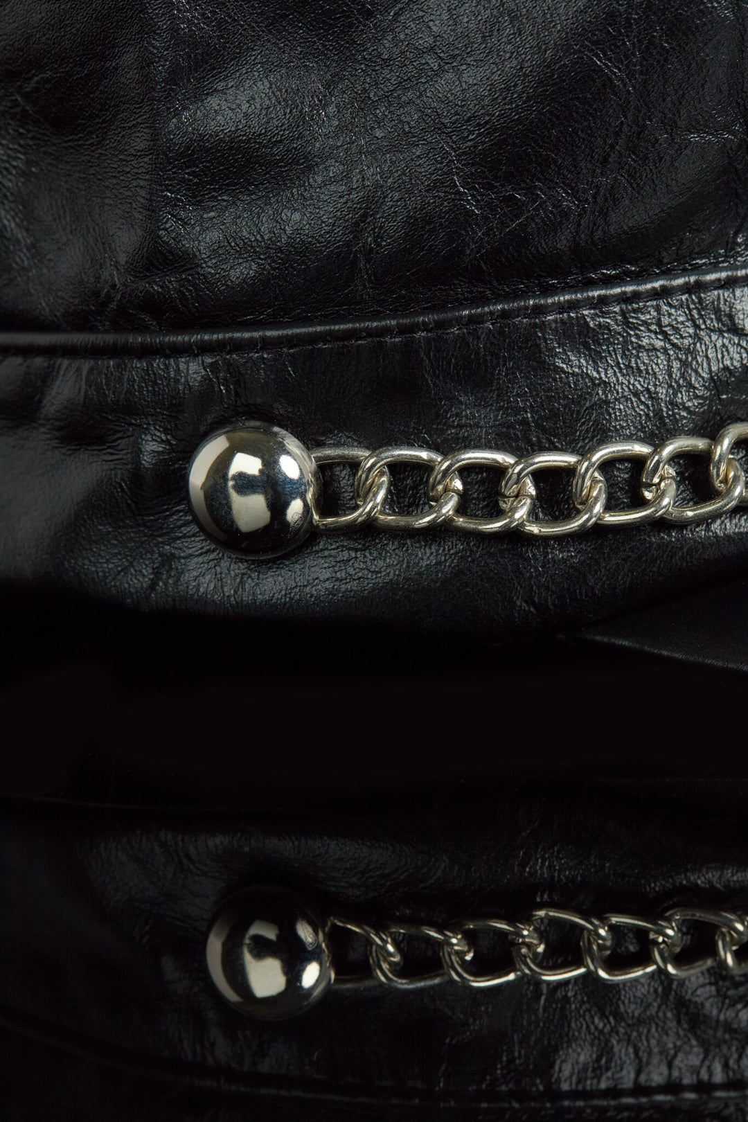 Close-up of a black leather cap with silver chain details
