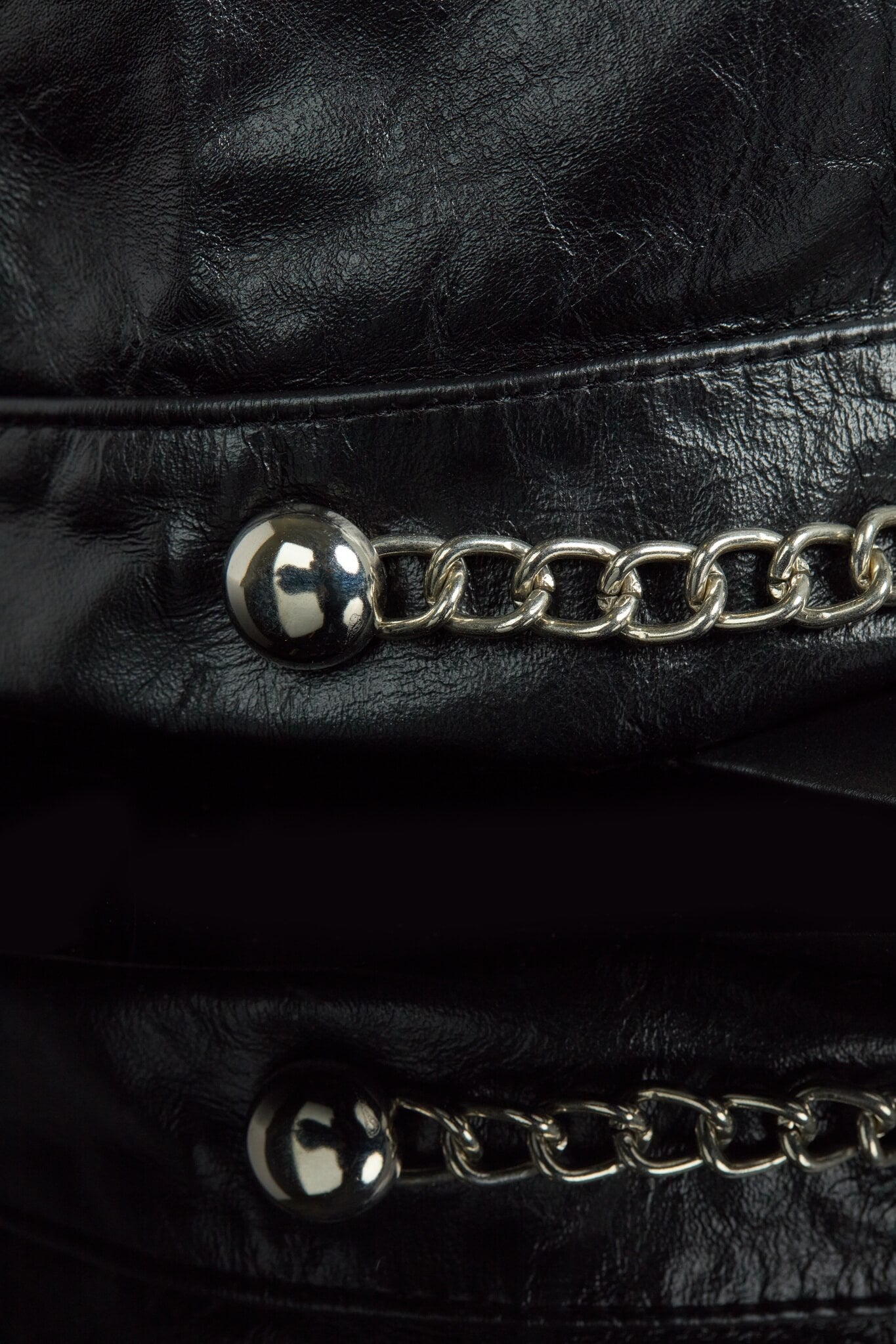 Close-up of a black leather cap with silver chain details