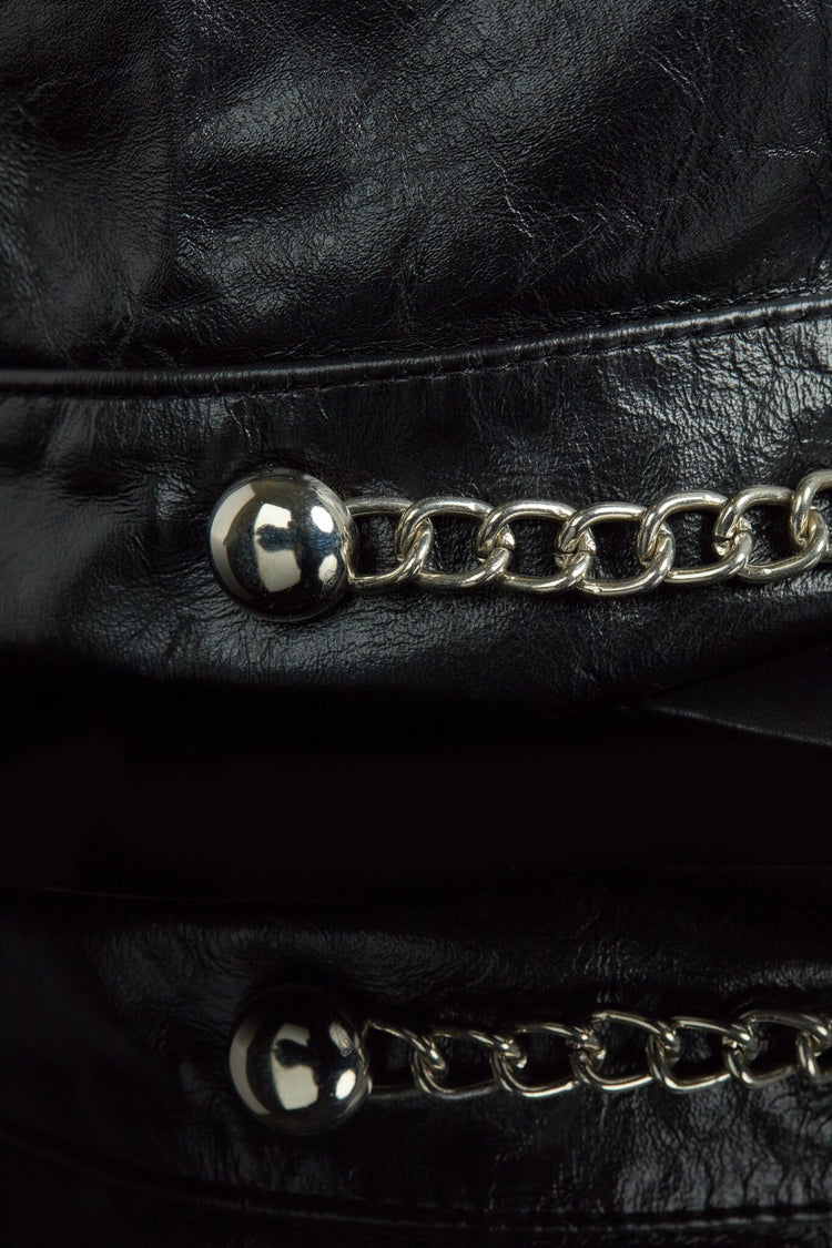 Close-up of a black leather cap with silver chain details