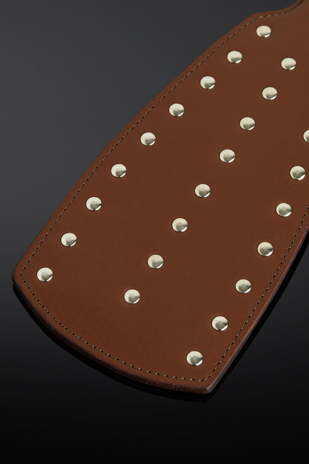 Photo of a brown leather paddle with closeup of the rivets. 