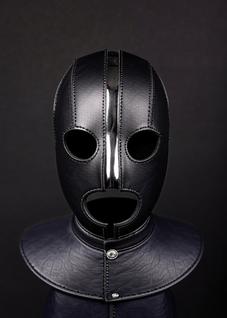 A photo showing a leather bondage hood. It  is black color with leather panels and metal buttons. 