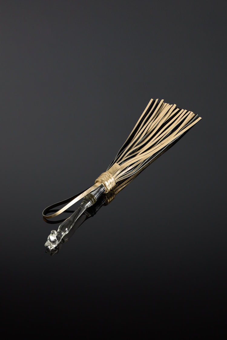 Gold leather whip with glass handle on a black background