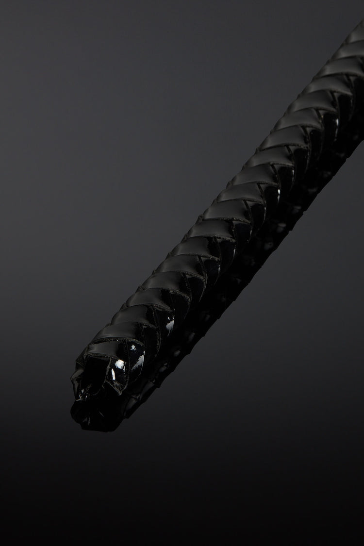 Close-up of a black textured leather tail tip on a dark background