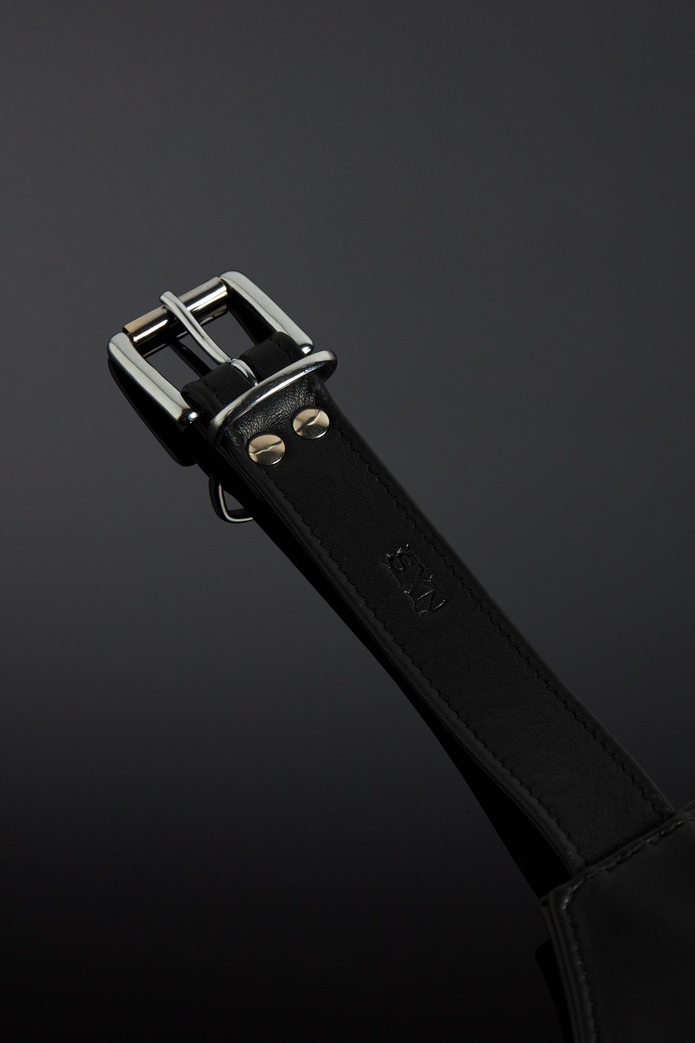 Black leather strap close up pic with silver buckle on a dark background