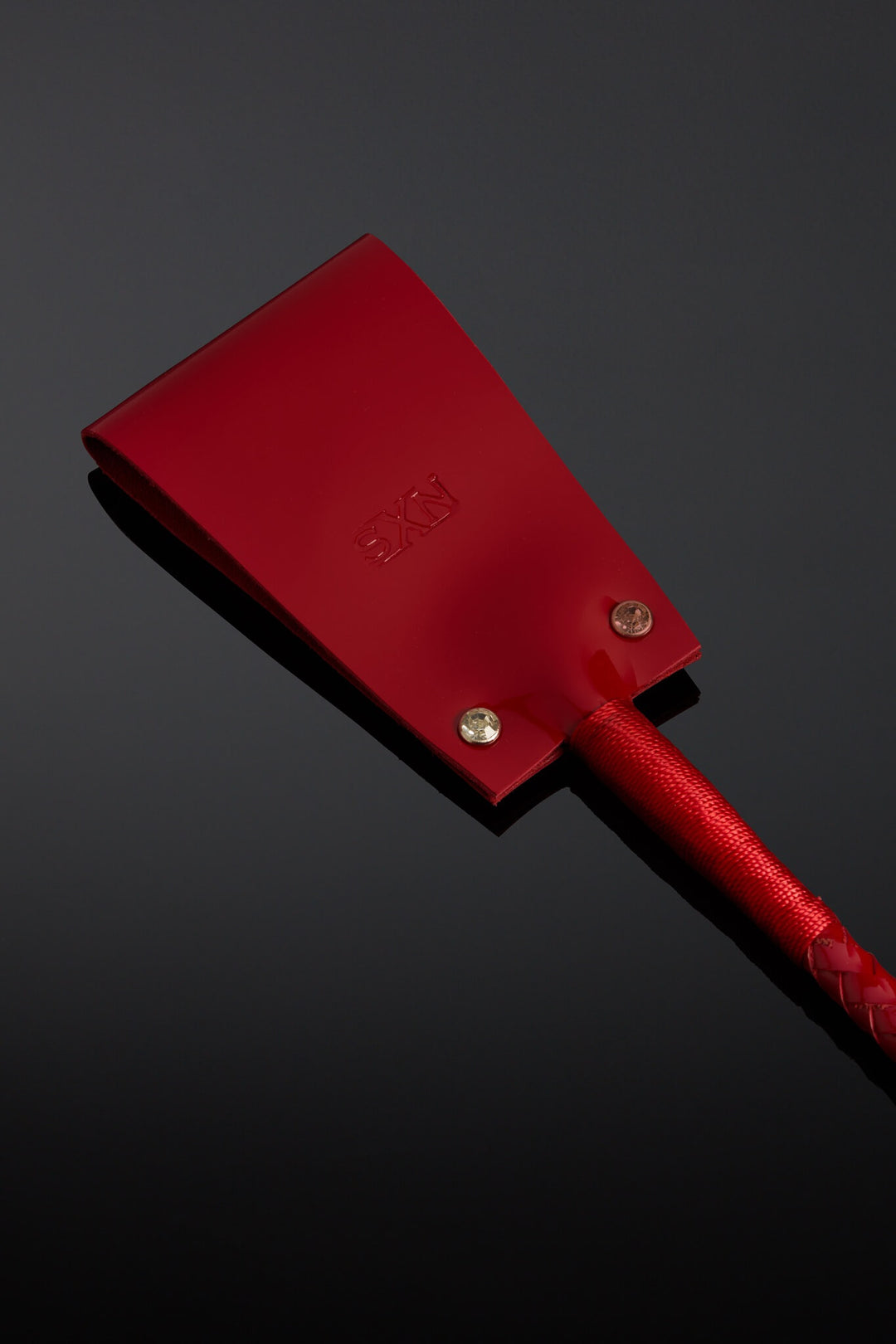 Picture of shiny red leather crop on a black background. 