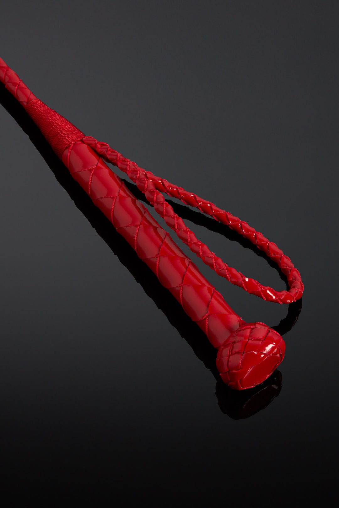 Red leather crop handle on black background