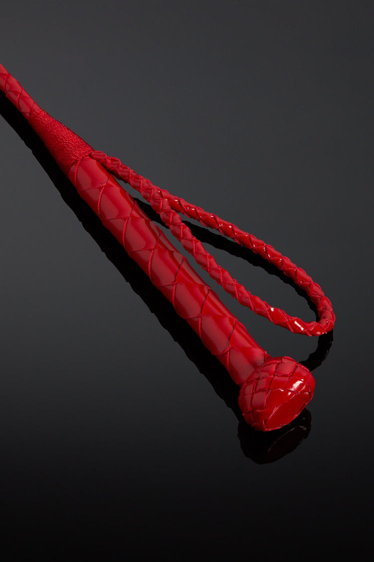 Red leather crop handle on black background