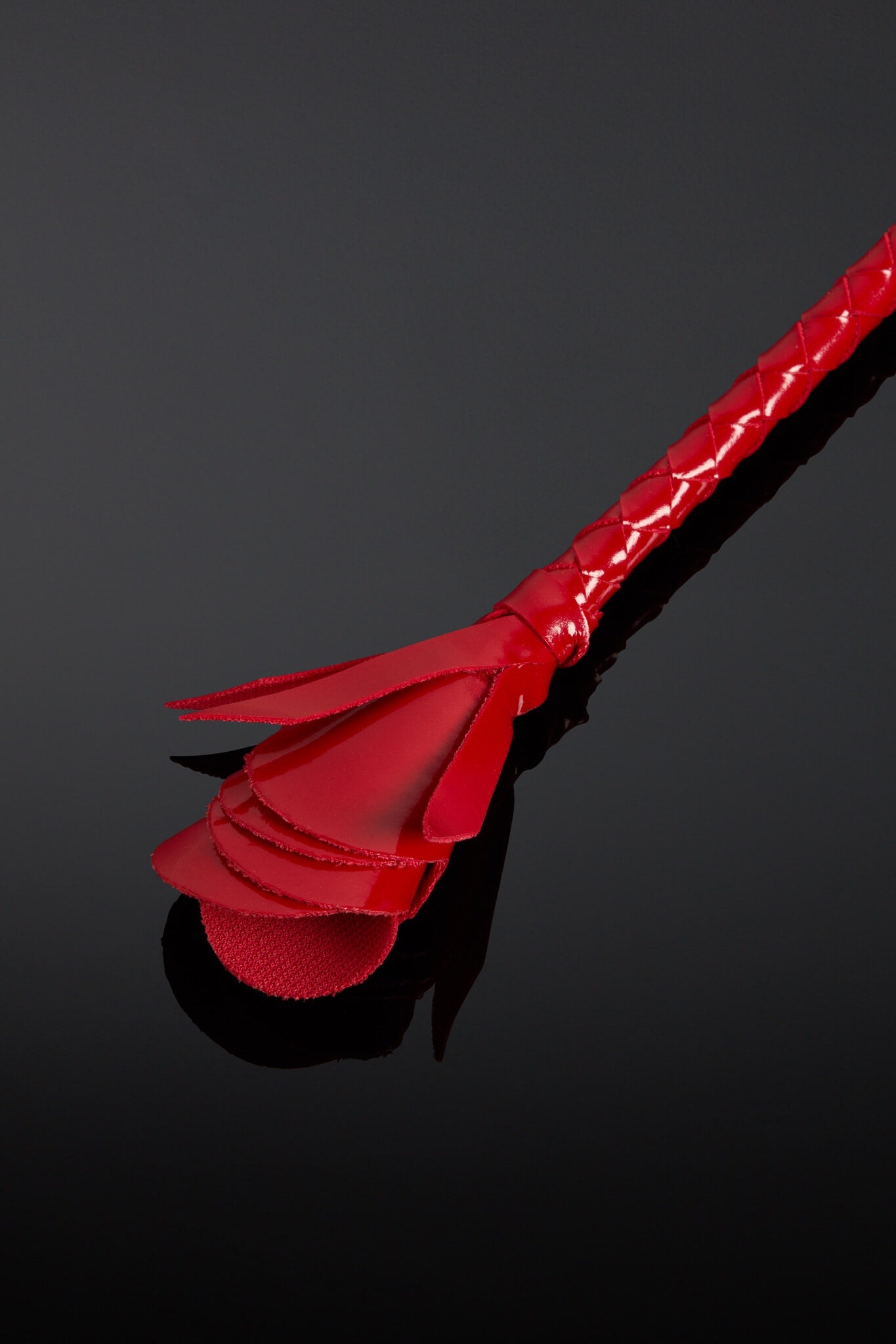 Red leather crop on a black background. Closeup of head which is shaped like a rose