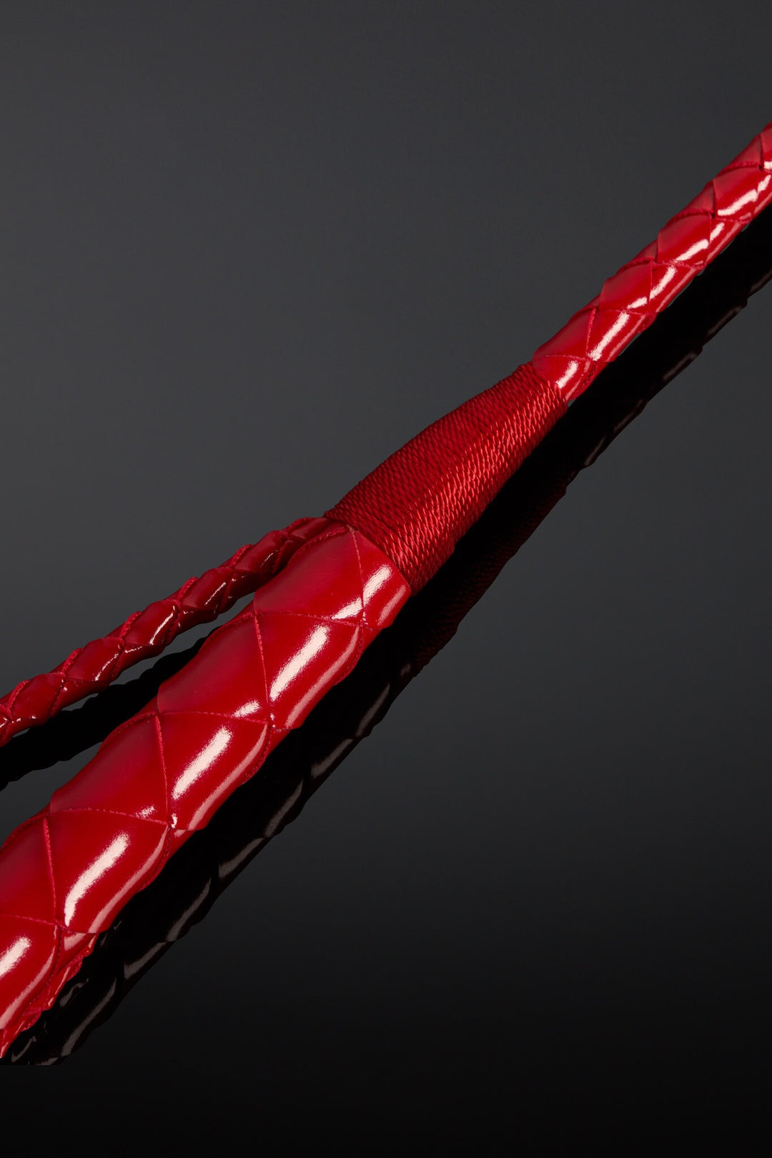 Closeup of leather crop. Red color on black background