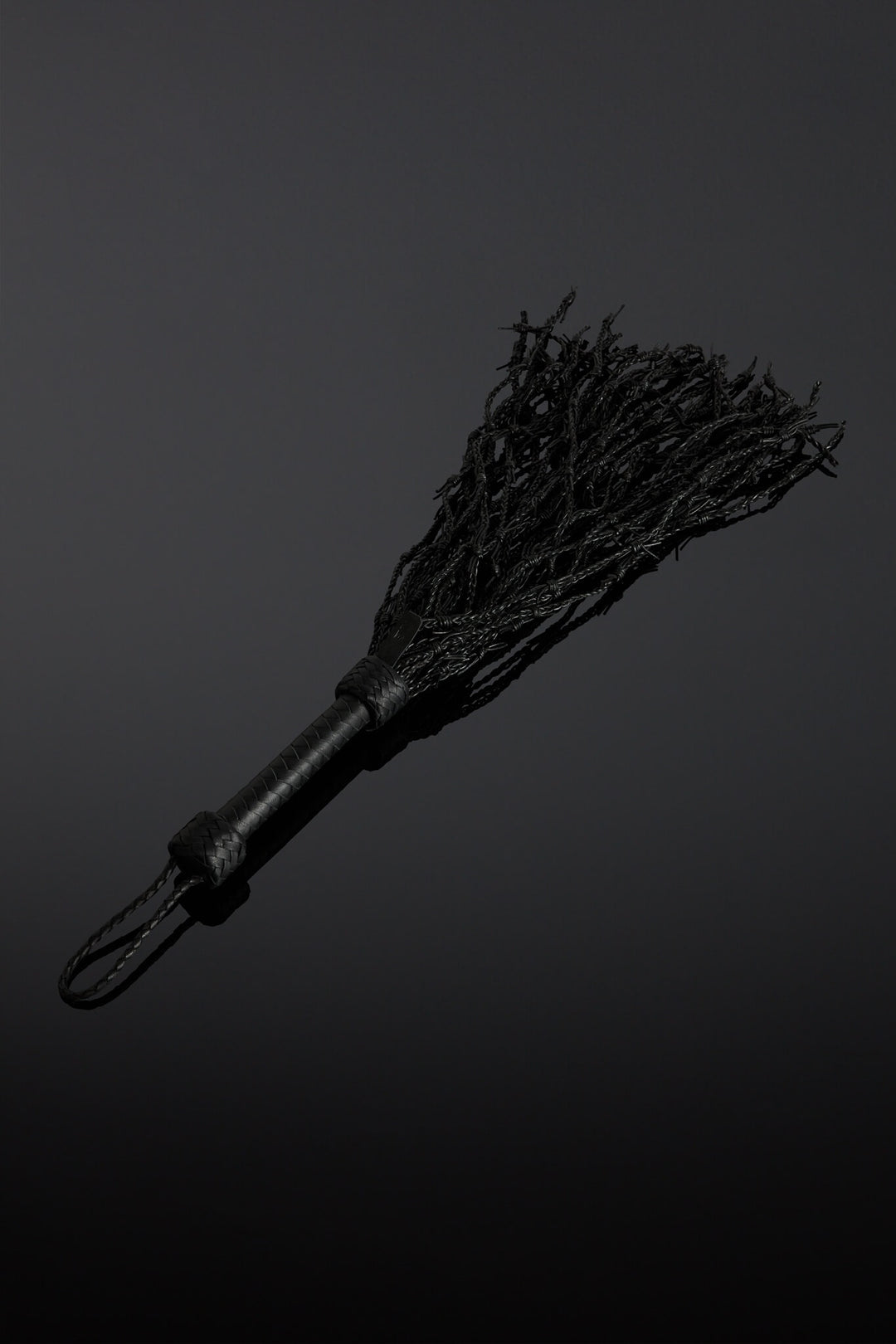 Black barbed wire looking flogger on dark background