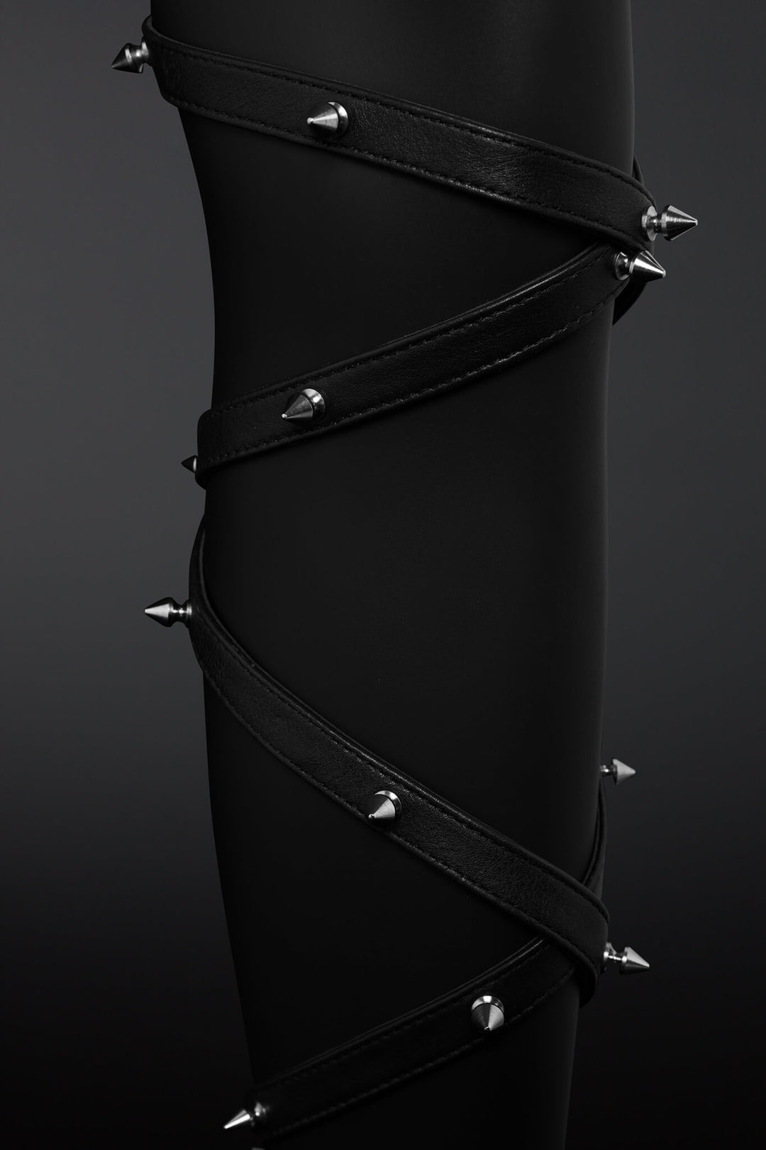 Clseup shot of leather straps wrapped around mannequin leg and showing off metail spikes