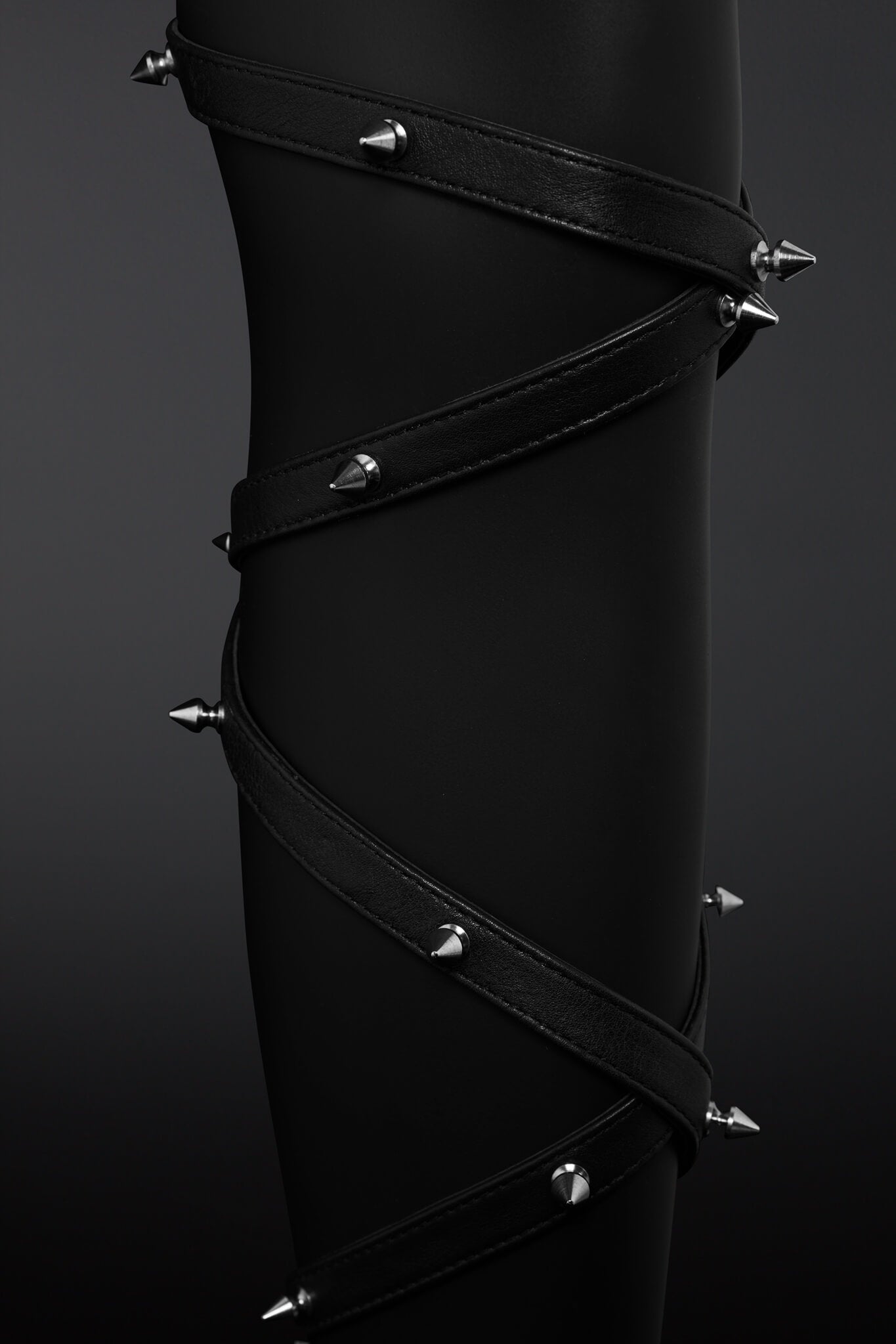 Clseup shot of leather straps wrapped around mannequin leg and showing off metail spikes
