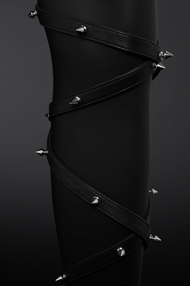 Clseup shot of leather straps wrapped around mannequin leg and showing off metail spikes