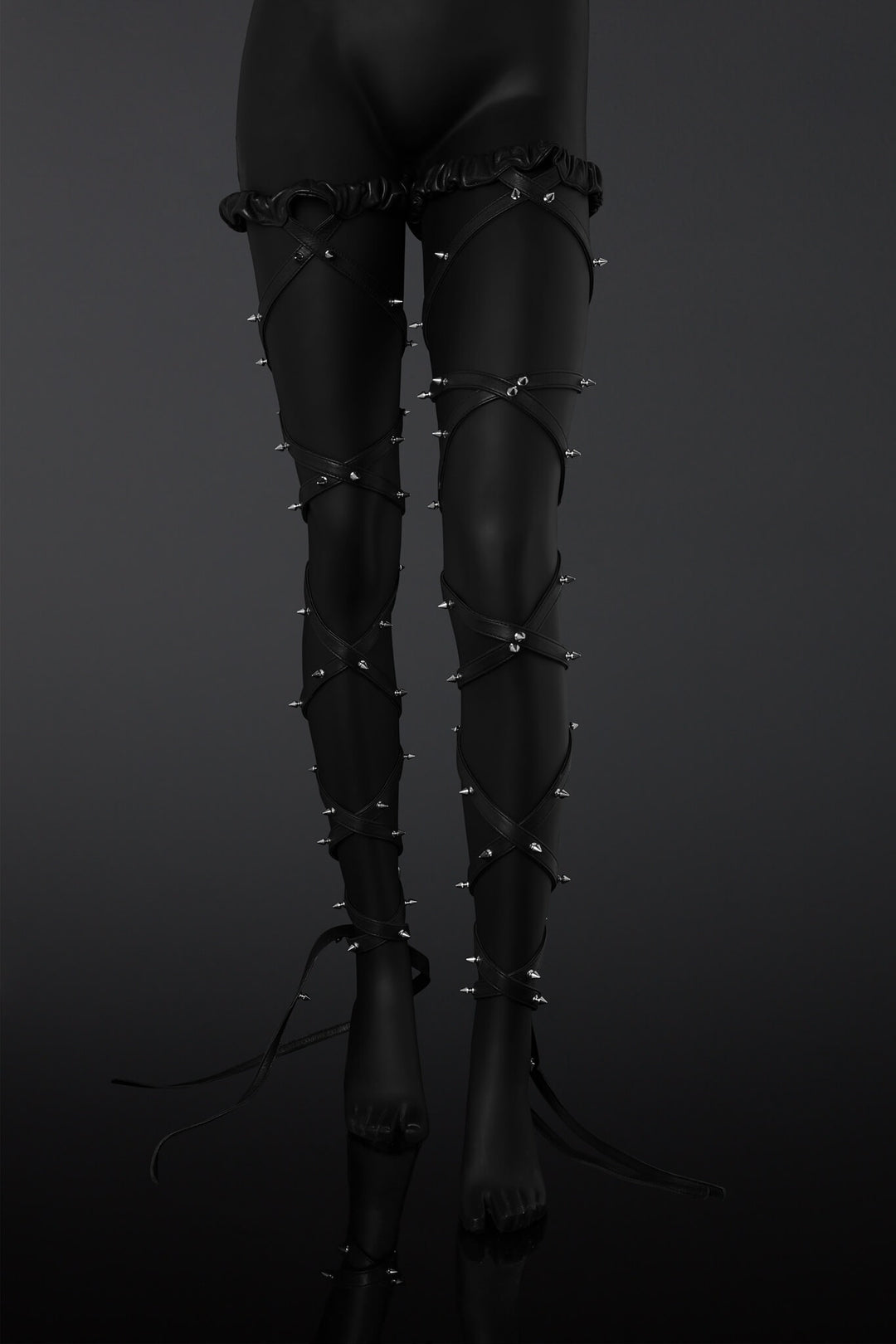 Black leather leg straps with metal spikes designs on a  mannequin legs over a dark background