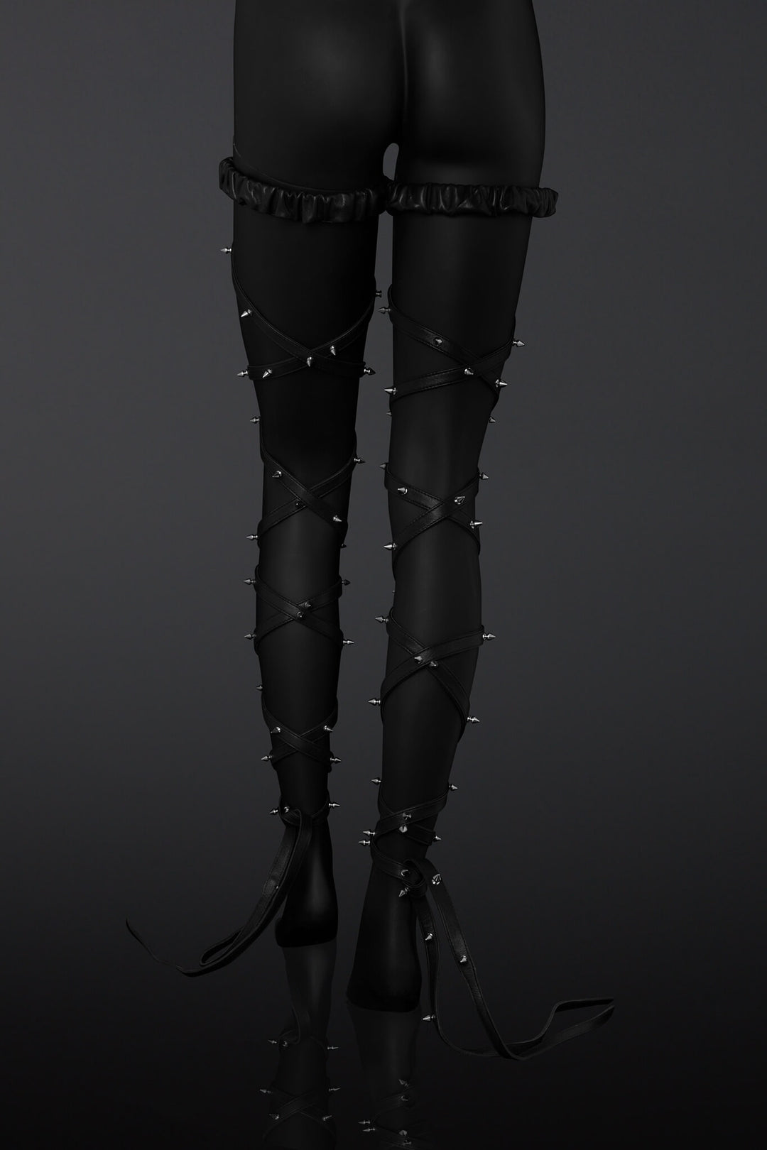 Black leather leg straps with metal spikes designs on a  mannequin legs over a dark background