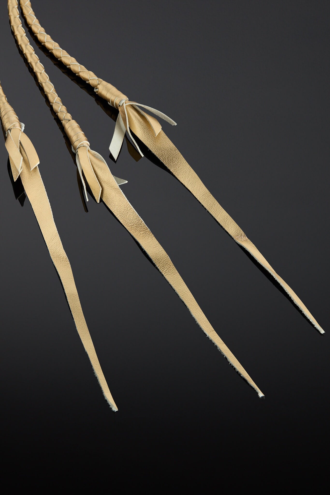 Three leather straps with braided ends on a black background
