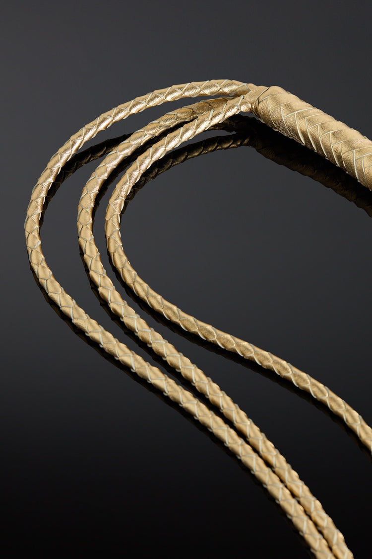Close-up of braided gold leather cord on a dark background
