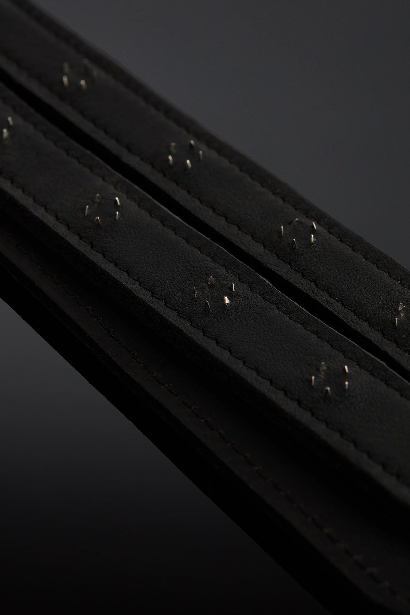 Close-up of a black leather belt tail with a dark background