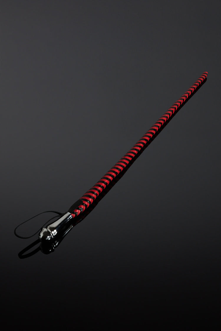 Red and black braided leather whip on a dark gray background